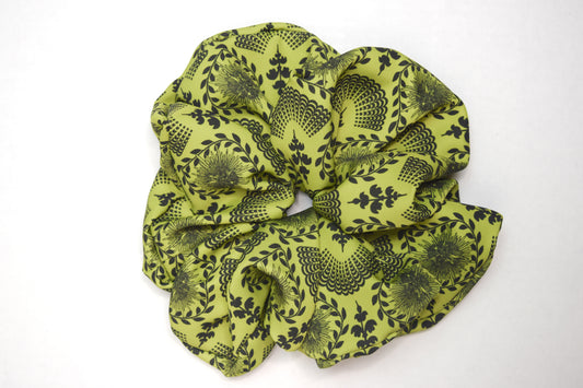 A bright chartreuse scrunchie with a carnival lady print, worn in a ponytail hairstyle by Ayiti Cherie