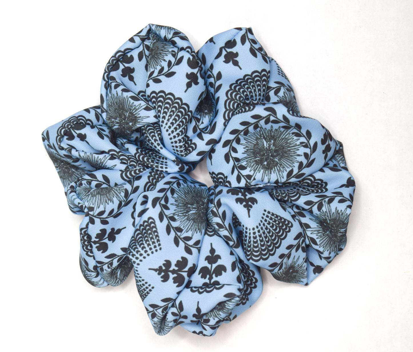 A sky blue scrunchie with a carnival lady print, worn in a ponytail hairstyle by Ayiti Cherie