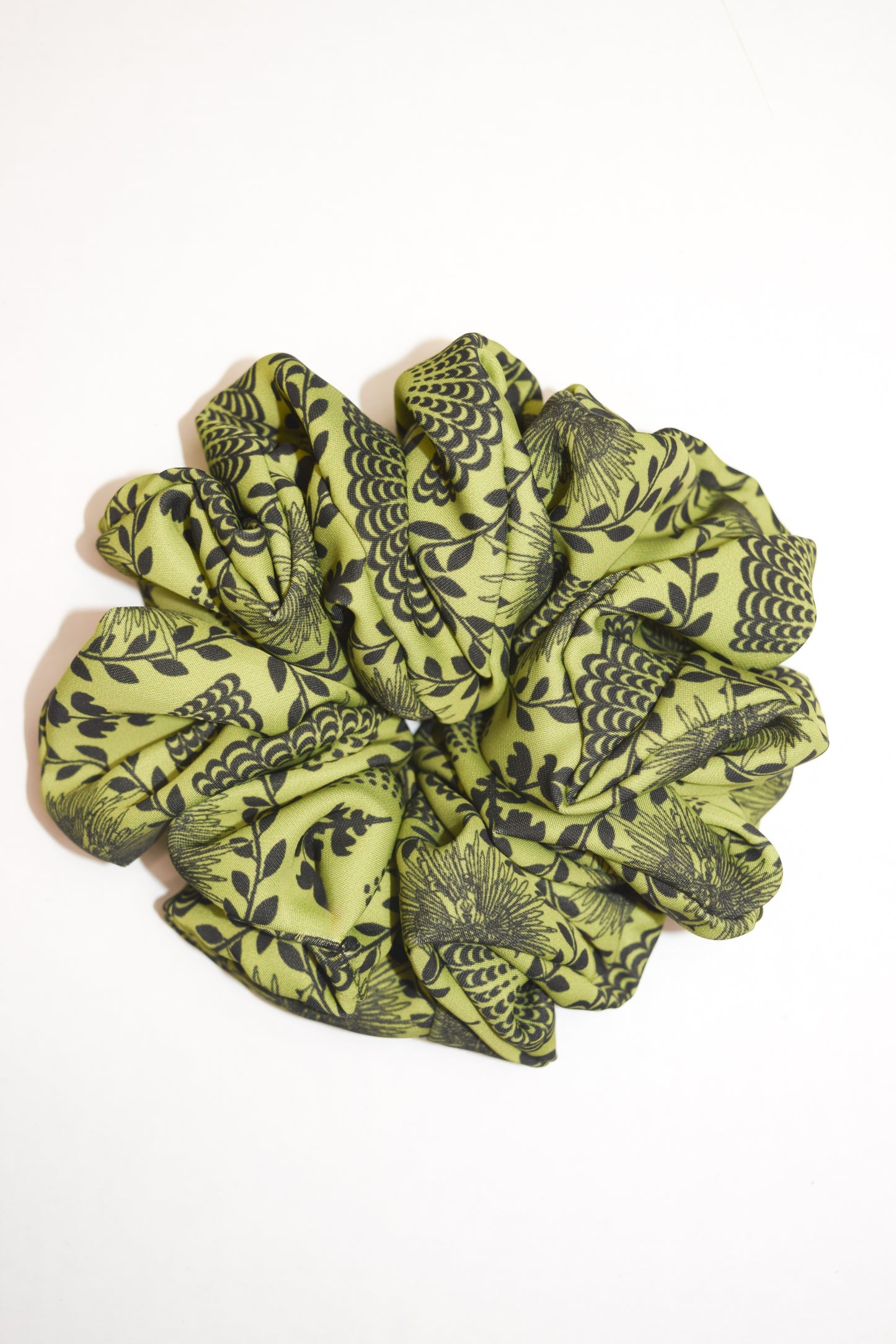 A bright chartreuse scrunchie with a carnival lady print, worn in a ponytail hairstyle by Ayiti Cherie