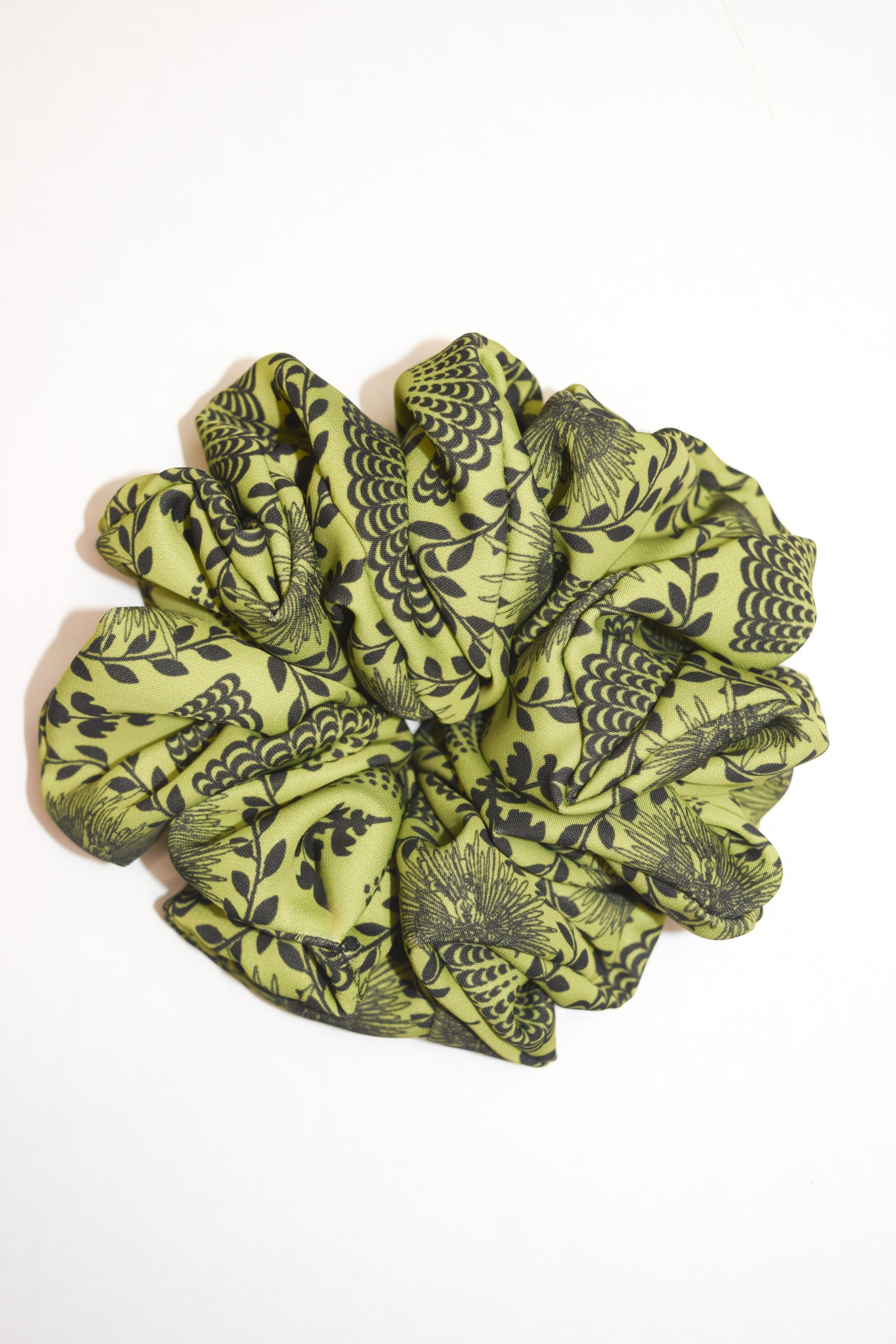A bright chartreuse scrunchie with a carnival lady print, worn in a ponytail hairstyle by Ayiti Cherie