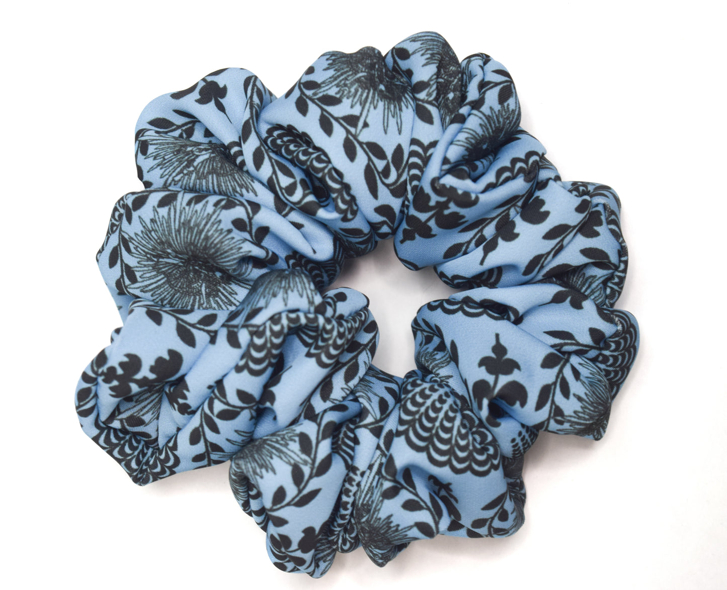 A sky blue scrunchie with a carnival lady print, worn in a bun hairstyle by Ayiti Cherie