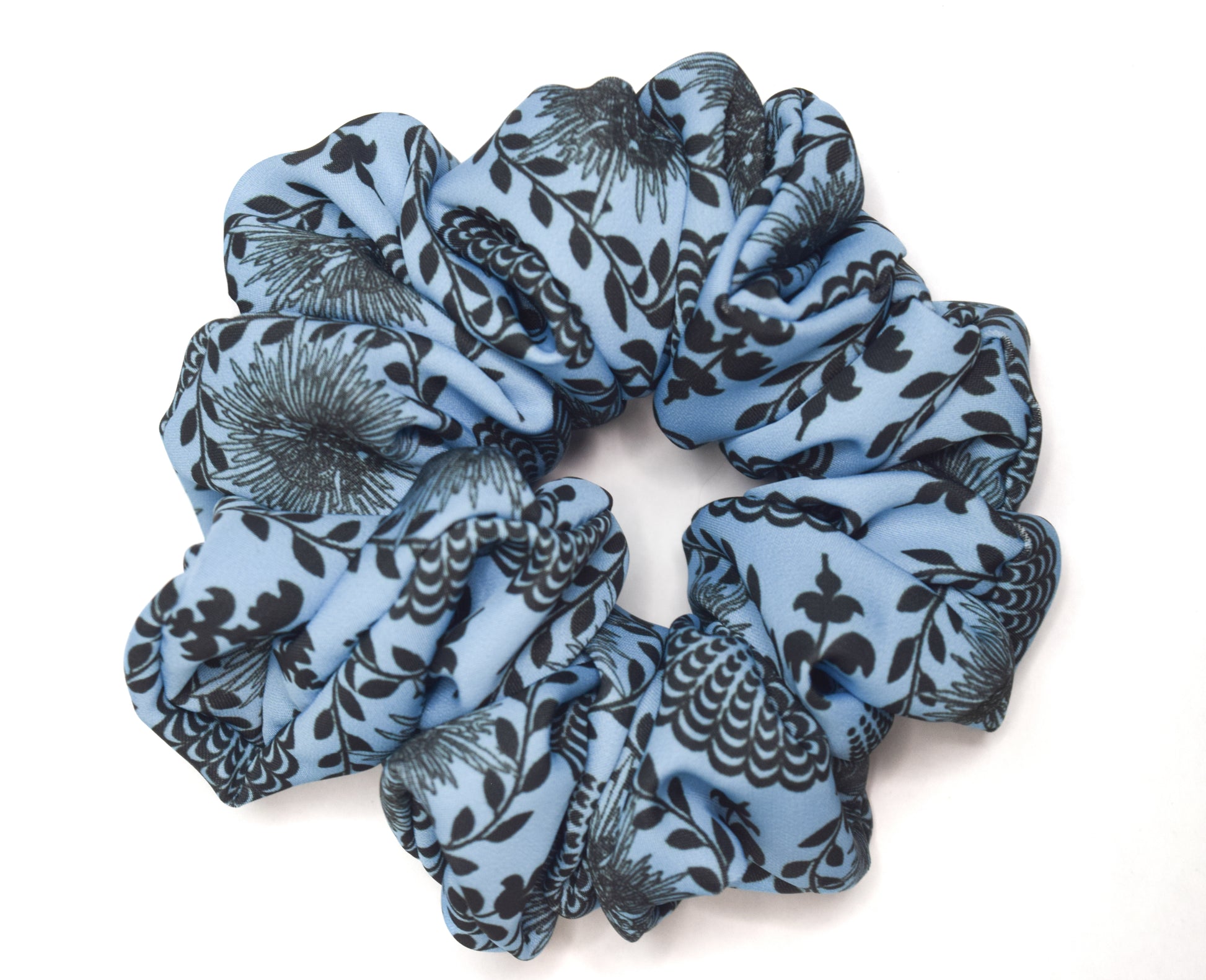 A sky blue scrunchie with a carnival lady print, worn in a bun hairstyle by Ayiti Cherie